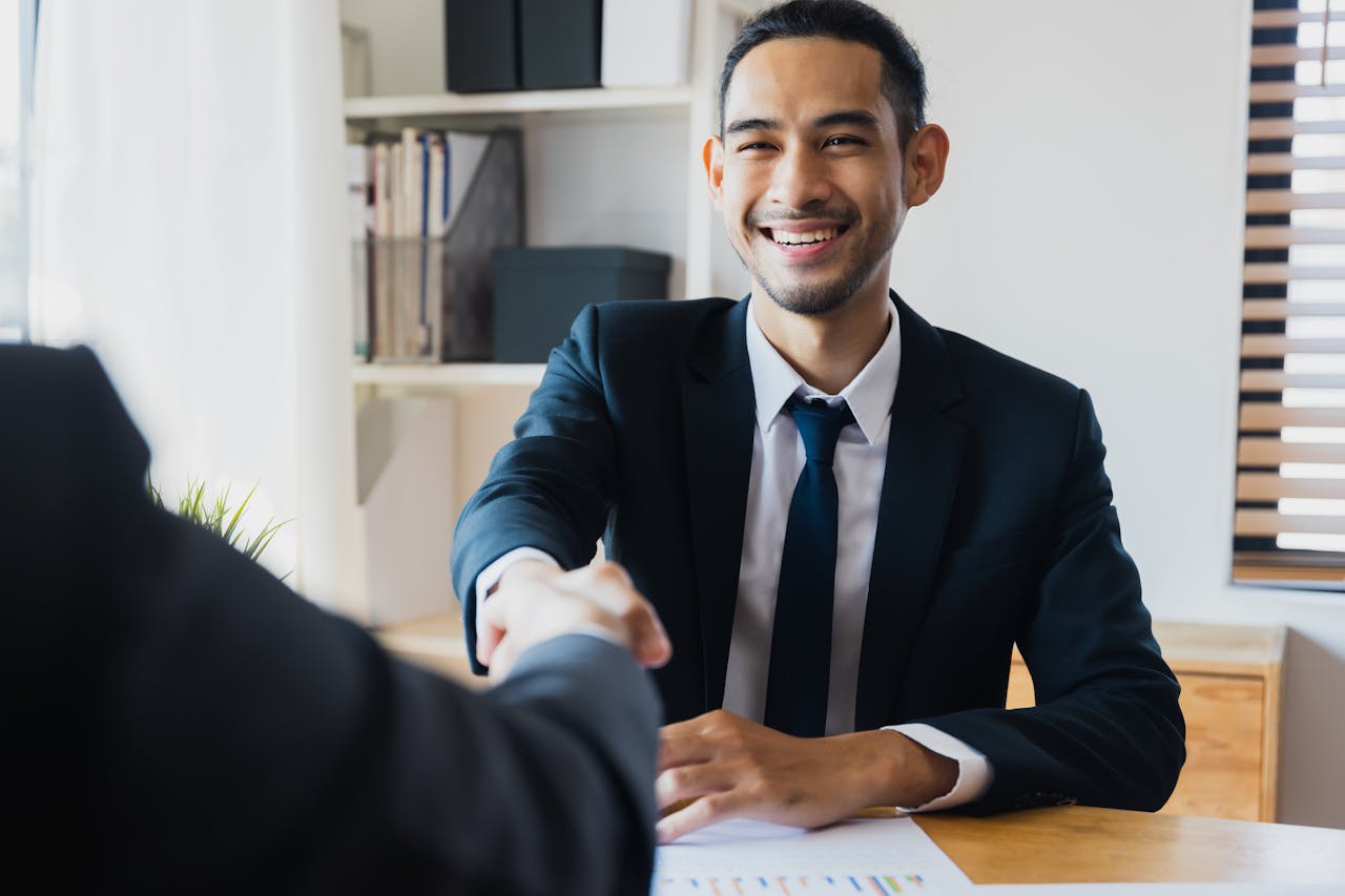 Services Confident businessman in suit shaking hands at office desk, symbolizing successful partnership.
